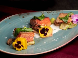 Platillo de carne servido con vegetales y flores comestibles